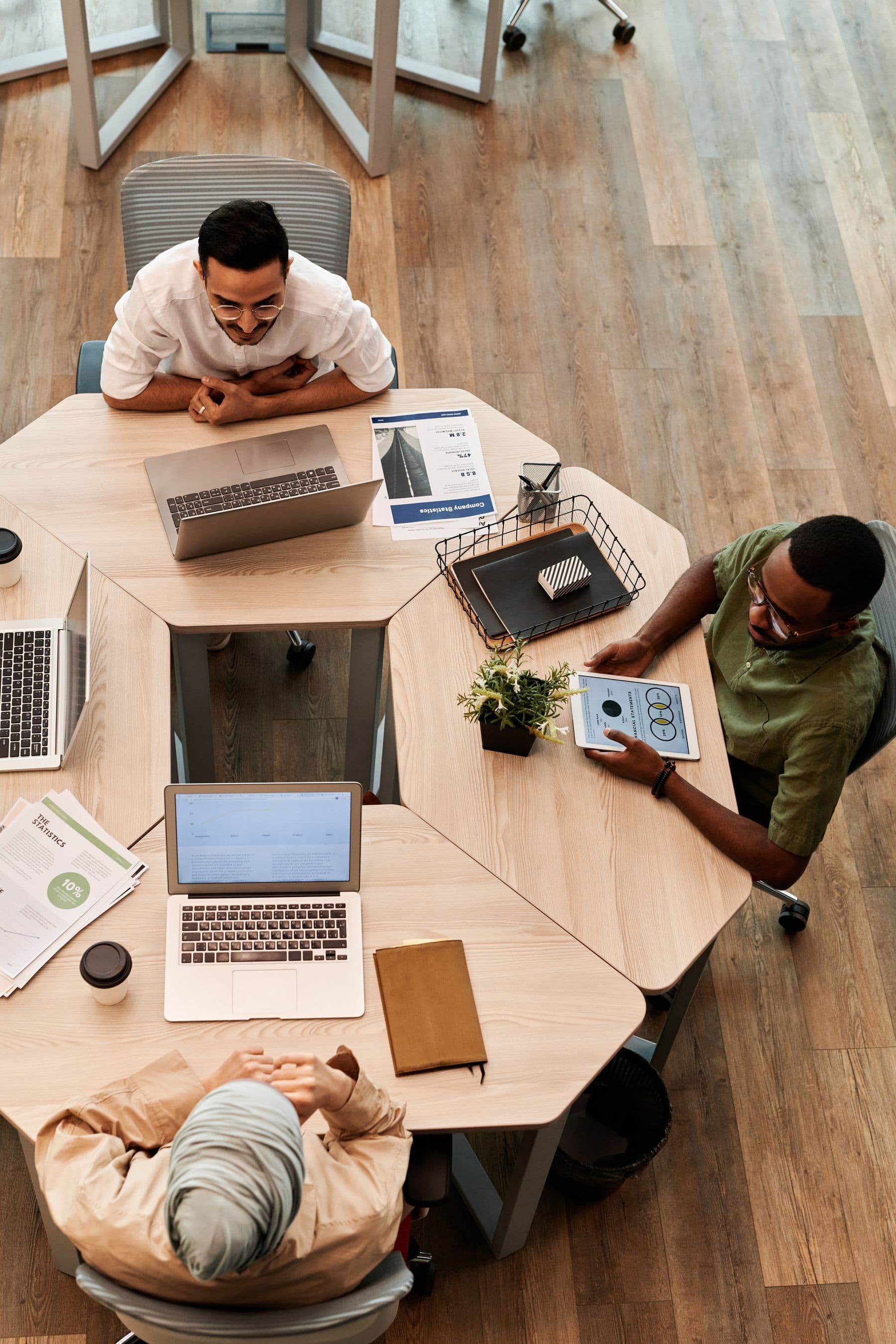 A team collaborating around a table with laptops and documents